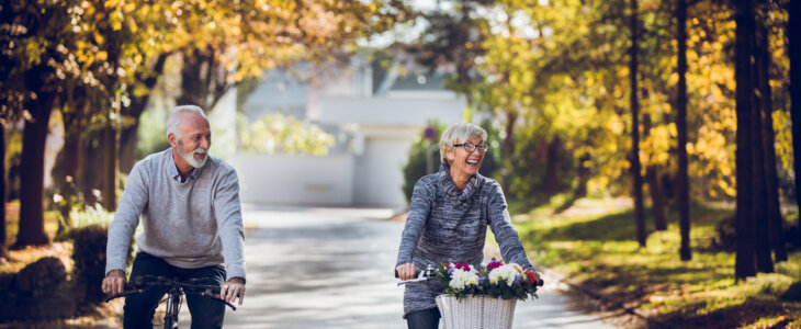 Senior couple riding bikes down an autumn street